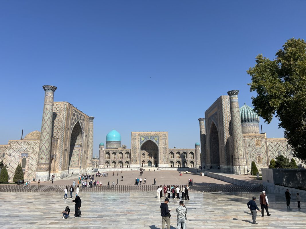 Historic architecture featuring ornate buildings with domes and minarets, bustling with visitors under a clear blue sky.